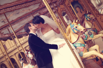 groom and bride kissing in a carousel