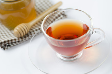 a cup of tea with honey on white background