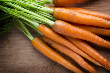 Fresh carrots on the wooden background.