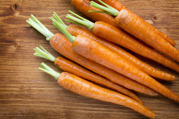 Fresh carrots on the wooden background.