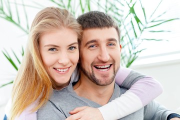 Fototapeta premium 50s. Smiling woman hugging her husband on the couch from behind