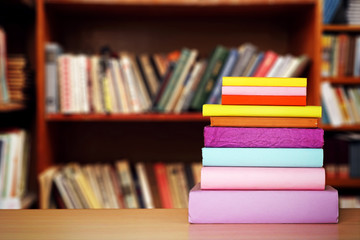 Stack of books on table on bookshelves background