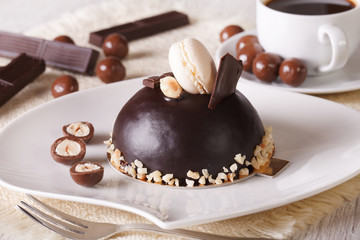 chocolate cake with nuts, macaroon on a plate  and coffee