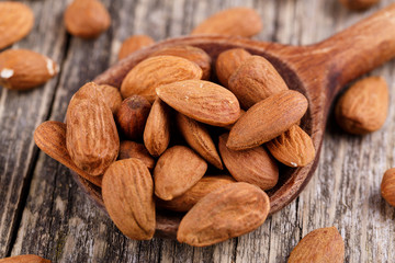 Almonds on a spoon on a wooden background.