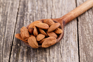 Almonds on a spoon on a wooden background.