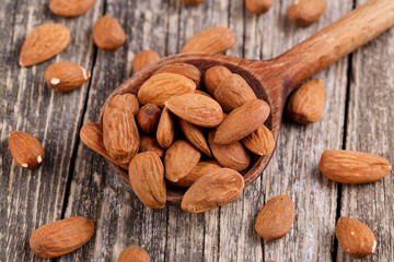 Almonds on a spoon on a wooden background.