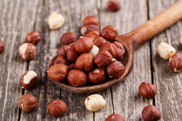 Hazelnuts on a spoon on wooden background.