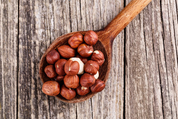 Hazelnuts on a spoon on wooden background.