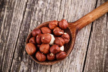 Hazelnuts on a spoon on wooden background.