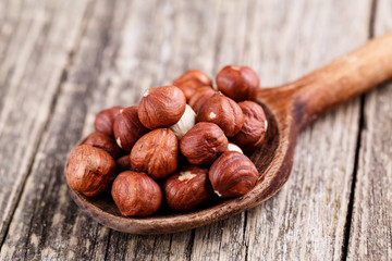 Hazelnuts on a spoon on wooden background.