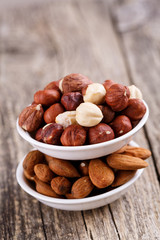 Hazelnuts and almonds on white plates.