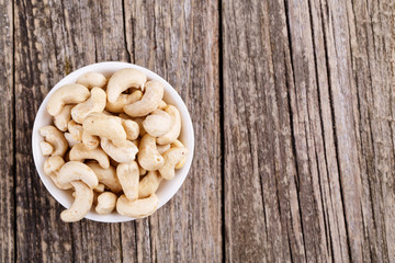 Cashew nuts on a plate on wooden background.