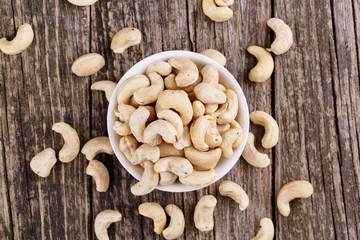 Cashew nuts on a plate on wooden background.