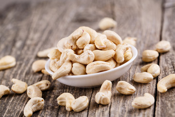 Cashew nuts on a plate on wooden background.