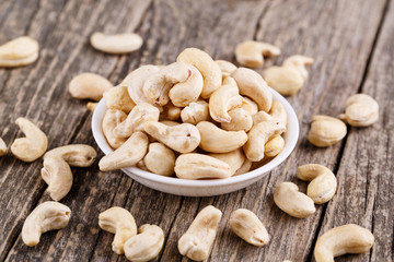 Cashew nuts on a plate on wooden background.
