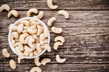 Cashew nuts on a plate on wooden background.