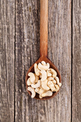 Brazil nuts on a spoon on wooden background.