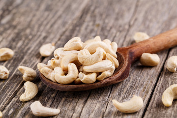 Brazil nuts on a spoon on wooden background.