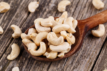 Brazil nuts on a spoon on wooden background.