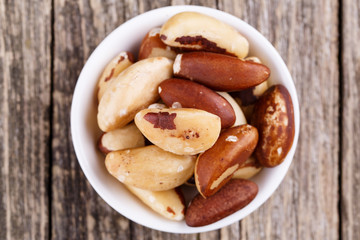Brazil nuts on a spoon on wooden background.