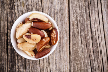 Brazil nuts on a spoon on wooden background.