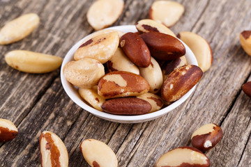 Brazil nuts on a spoon on wooden background.