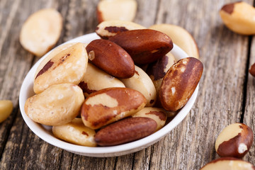 Brazil nuts on a spoon on wooden background.