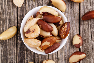 Brazil nuts on a spoon on wooden background.