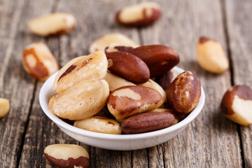 Brazil nuts on a spoon on wooden background.