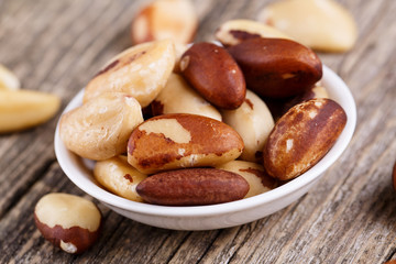 Brazil nuts on a spoon on wooden background.