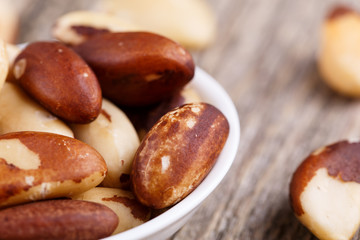 Brazil nuts on a spoon on wooden background.