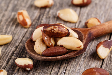 Brazil nuts on a spoon on wooden background.