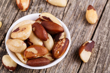 Brazil nuts on a spoon on wooden background.