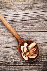 Brazil nuts on a spoon on wooden background.