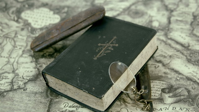 The bible eyeglass and the razor on the map