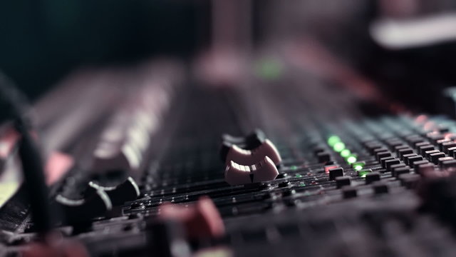 Audio Engineer adjusting faders on his mixing console desk