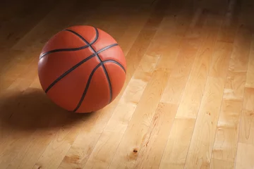 Foto auf Acrylglas Basketball on hardwood court floor with spot lighting © Daniel Thornberg