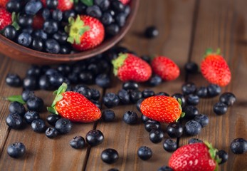 Assorted. Mix of fresh berries in a basket on rustic wooden