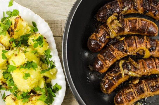 Roasted sausage with potatoes on wooden table