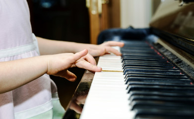 Fototapeta premium Girl's hands and piano keyboard close-up view