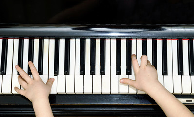 Girl's hands and piano keyboard close-up view