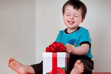 Happy toddler boy opening gift box