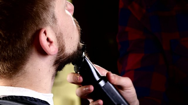 Master barber shop haircut beard makes the client using machines