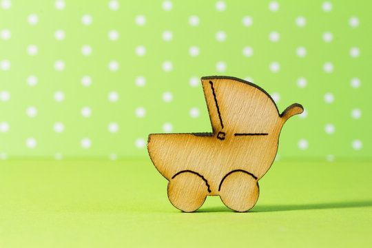Wooden icon of baby carriage on green background