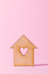 Obraz na płótnie Canvas Wooden house with hole in the form of heart on pink background