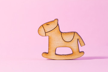 Wooden icon of children's rocking horse on pink background