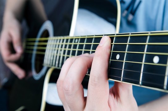 Close up of playing guitar. Musician holding a chord