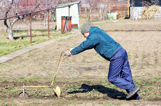 Man loosens the ground using an old plow