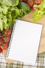 Obraz na płótnie Canvas Making preparing summer salad lettuce tomato ingredients on kitchen worktop counter with blank notebook cookbook or recipe book for copy photo vertical