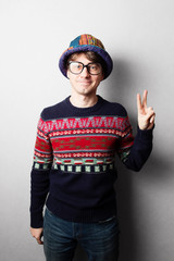 Young handsome man in knit colourful clothes, gray wall behind